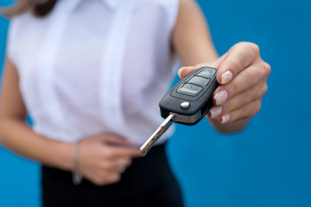 How to finance a private car sale; a woman on a blue background hands car keys to the vehicle's new owner following a private sale