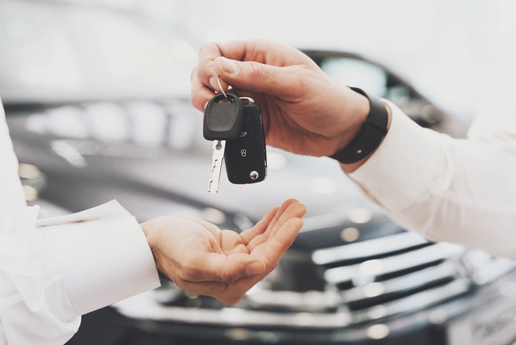 Car seller hands over keys of vehicle to buyer to complete the transfer of vehicle ownership