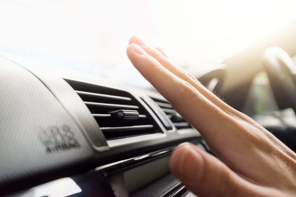 Closeup of a hand checking the air conditioner in a car, one of the main differences between American specs vs GCC specs.