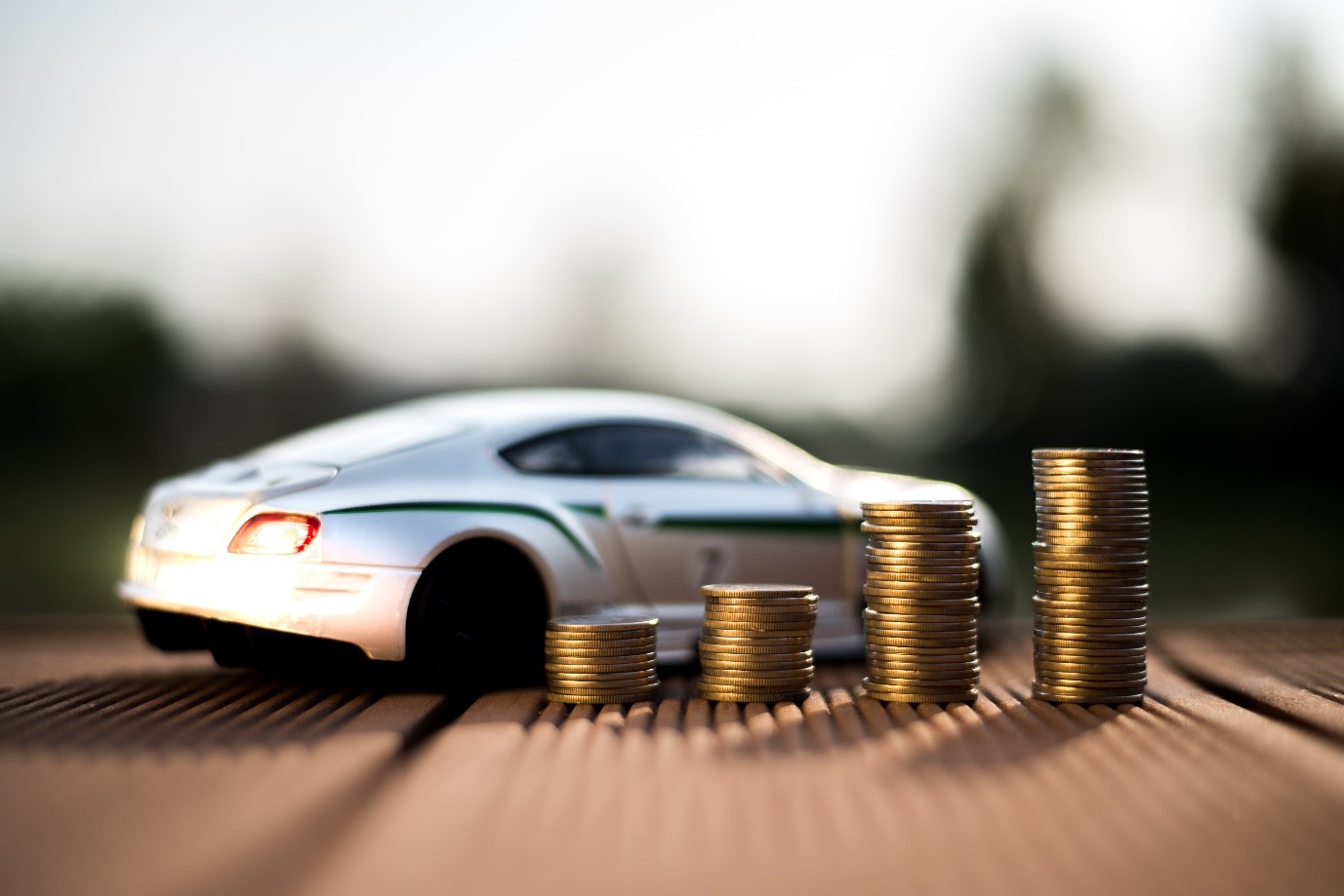 How to get a car on finance and save money for a car; a silver car next to increasingly large stacks of money.