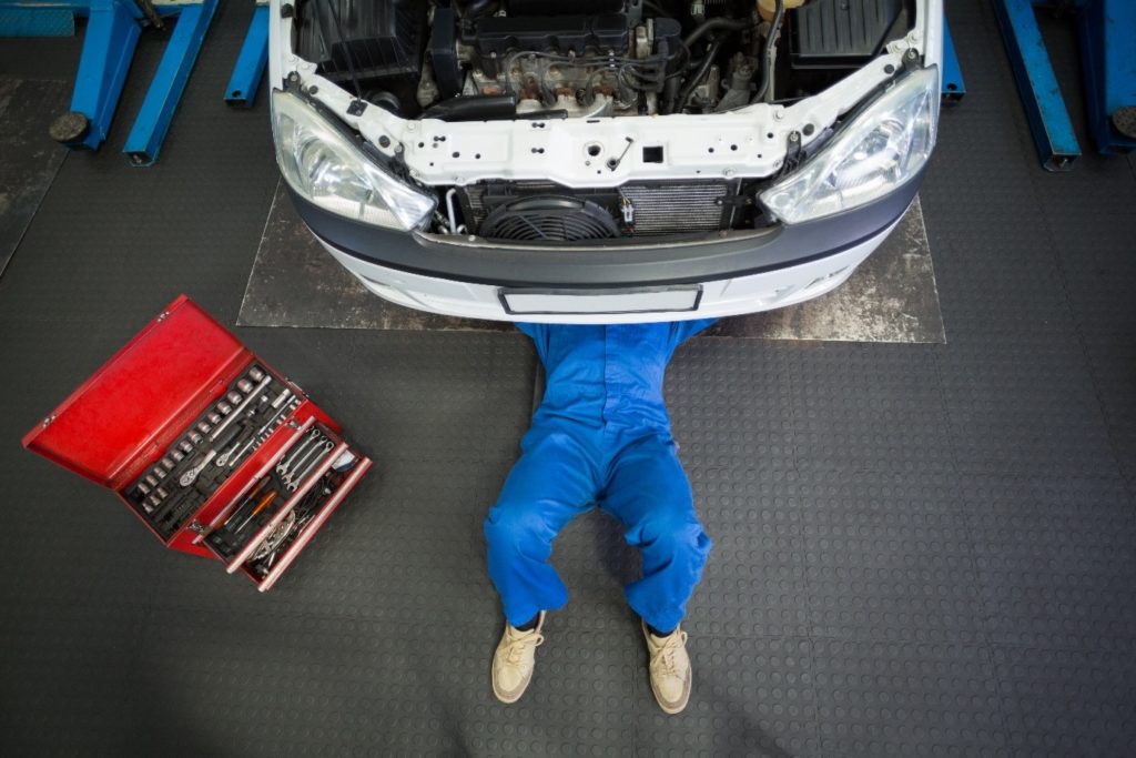 A difference between GCC  specs and American specs can be the repair process; a mechanic lying and working under a white car to replace parts at the repair garage